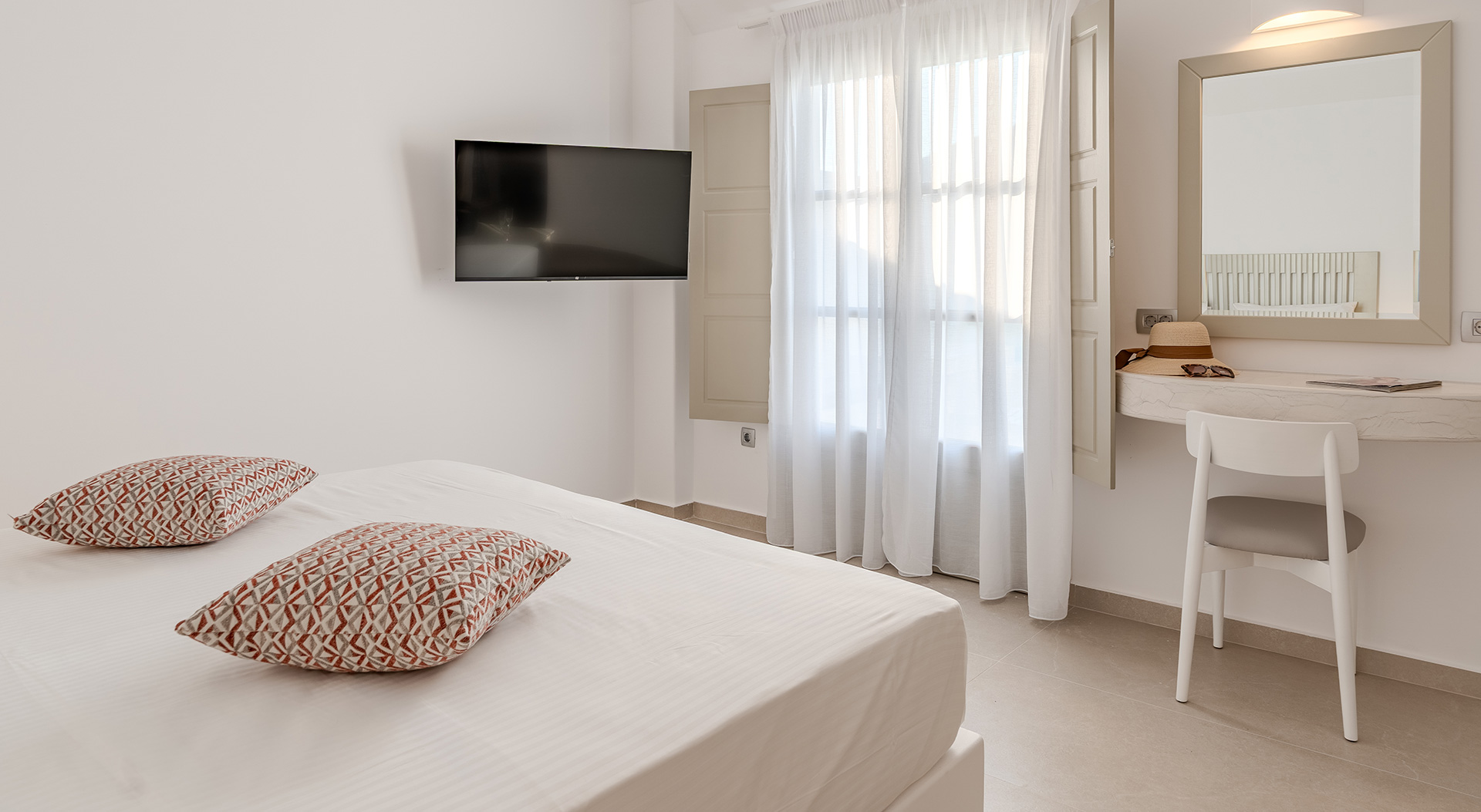 Signature Double Room with double bed, flat-screen TV and dressing table at Antoperla Adults Only Santorini Hotel