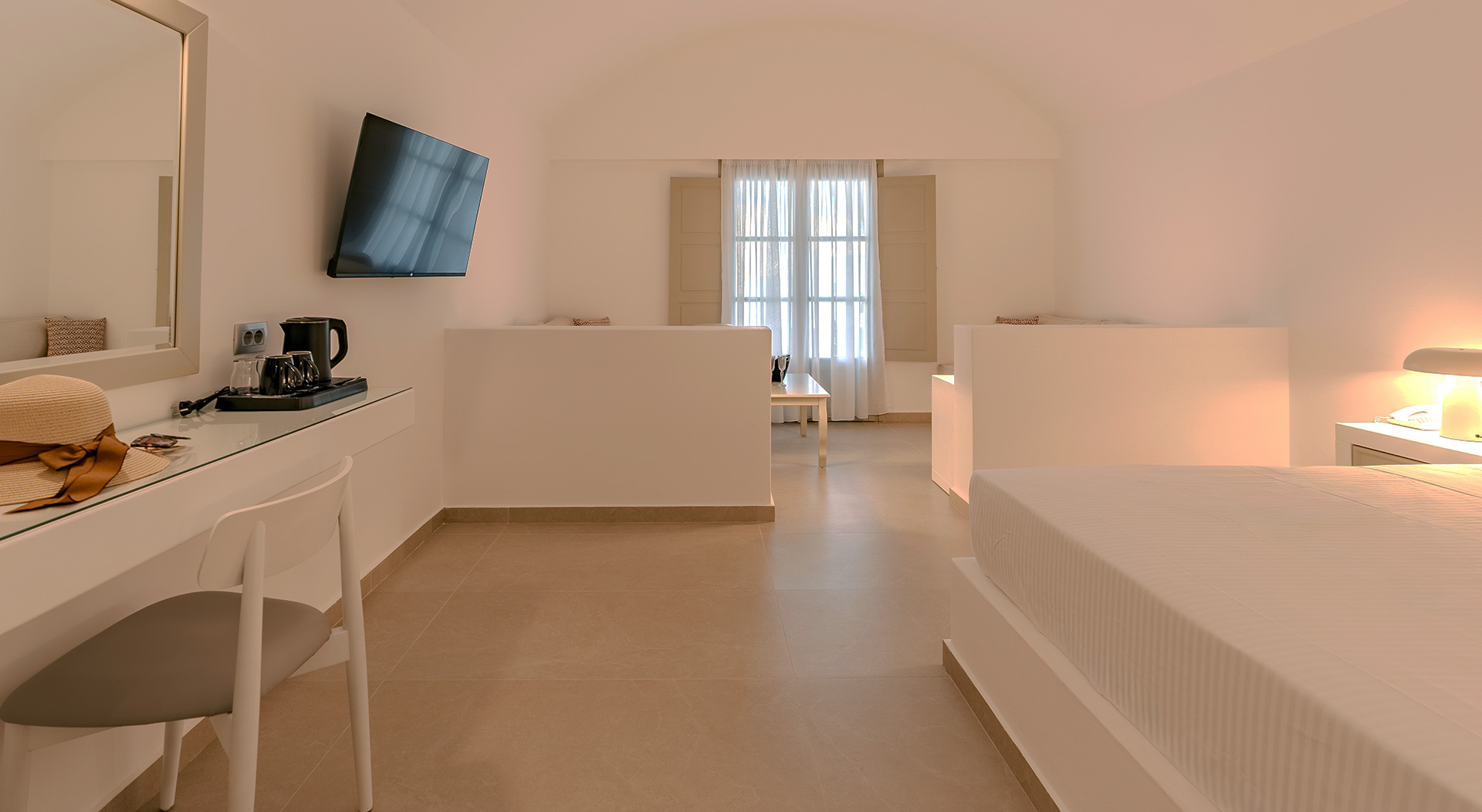 Spacious interior with bedroom, desk and lounge area in the Signature Open Plan Suite at Antoperla Adults Only Santorini Hotel